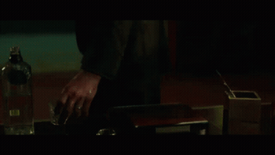 A Man With A Beard Is Standing In A Dark Room With The Word Peace Behind Him GIF