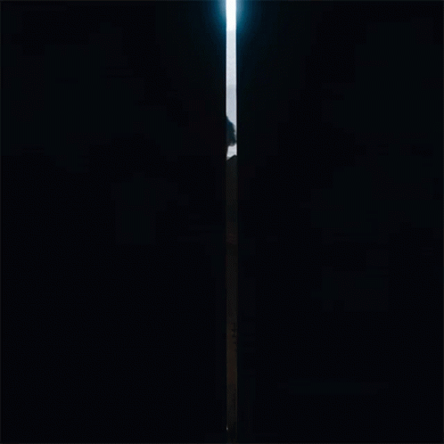 A Man With A Beard Is Standing In A Doorway Looking Out Over The Ocean GIF