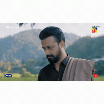 A Man With A Beard Is Standing In A Field With Mountains In The Background And A Advertisement For Itel On The Bottom Ri GIF