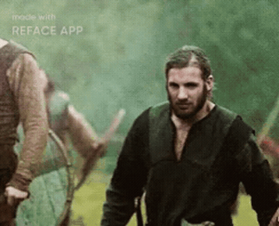 A Man With A Beard Is Standing In A Field With Other Men . GIF
