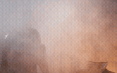 A Man With A Beard Is Standing In A Foggy Room With His Hands Outstretched . GIF