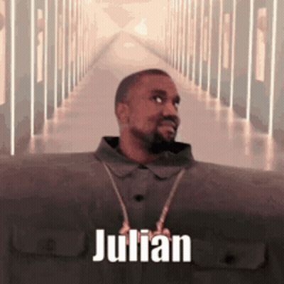 A Man With A Beard Is Standing In A Hallway With The Name Julian On It . GIF