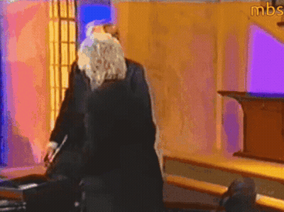 A Man With A Beard Is Standing In A Room With Mbs Written On The Wall GIF