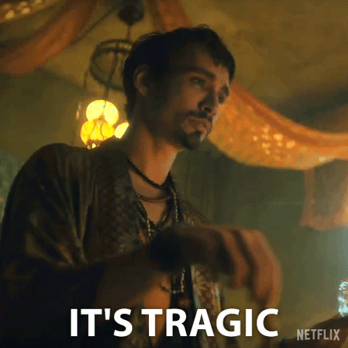 A Man With A Beard Is Standing In A Room With The Words `` It 'S Tragic '' Written On The Bottom . GIF