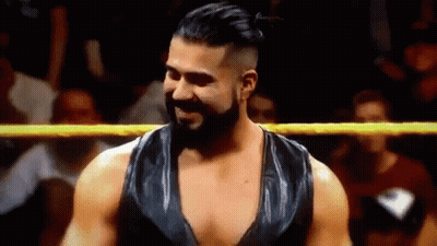 A Man With A Beard Is Standing In A Wrestling Ring And Smiling At The Camera . GIF