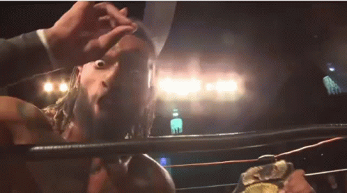 A Man With A Beard Is Standing In A Wrestling Ring Holding A Championship Belt . GIF