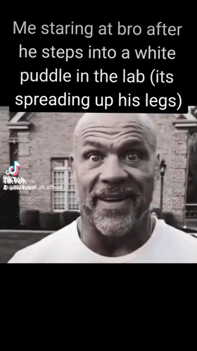 A Man With A Beard Is Standing In Front Of A Brick Building And Talking To Someone . GIF