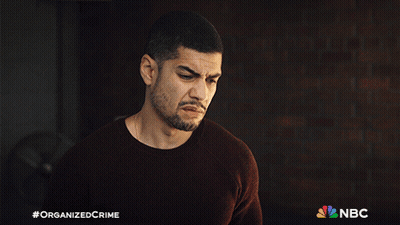 A Man With A Beard Is Standing In Front Of A Brick Wall With A Nbc Logo In The Corner GIF