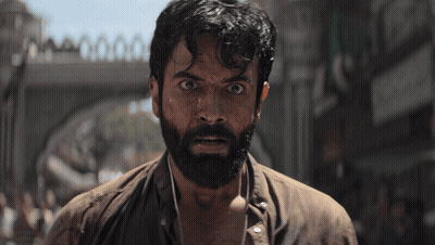 A Man With A Beard Is Standing In Front Of A Bridge GIF