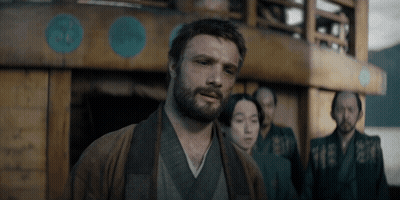 A Man With A Beard Is Standing In Front Of A Building GIF