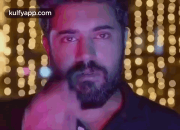 A Man With A Beard Is Standing In Front Of A Bunch Of Lights And Looking At The Camera . GIF