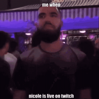 A Man With A Beard Is Standing In Front Of A Crowd In A Club . GIF