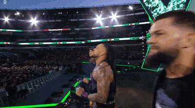 A Man With A Beard Is Standing In Front Of A Crowd In A Stadium With Green Lights GIF