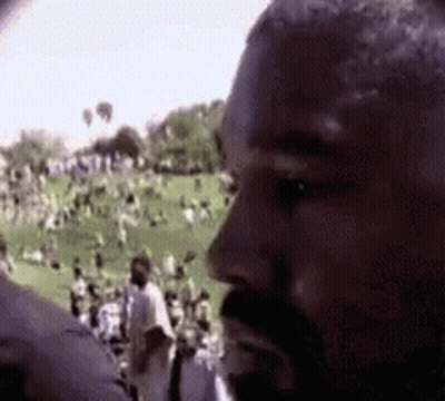 A Man With A Beard Is Standing In Front Of A Crowd . GIF