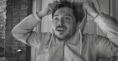 A Man With A Beard Is Standing In Front Of A Door With His Jacket On GIF