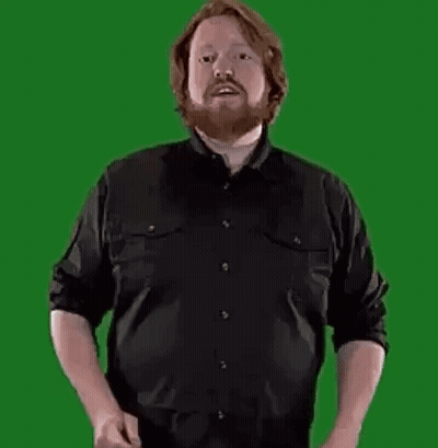 A Man With A Beard Is Standing In Front Of A Green Screen Holding A Large Letter B . GIF