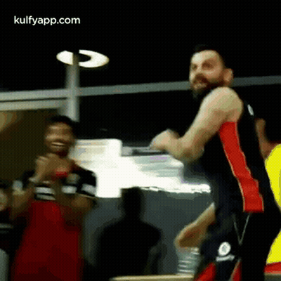 A Man With A Beard Is Standing In Front Of A Group Of People . GIF