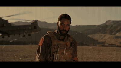 A Man With A Beard Is Standing In Front Of A Helicopter And Mountains GIF