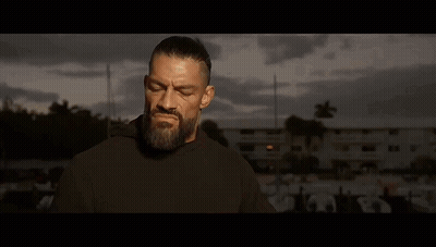 A Man With A Beard Is Standing In Front Of A Man With His Hands Folded . GIF