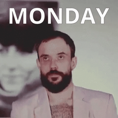 A Man With A Beard Is Standing In Front Of A Monday Poster GIF
