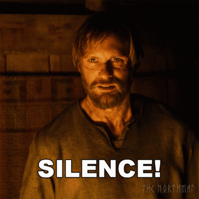 A Man With A Beard Is Standing In Front Of A Poster That Says Silence GIF