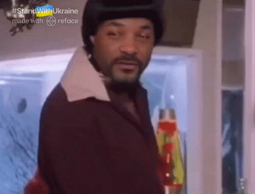 A Man With A Beard Is Standing In Front Of A Refrigerator With #Standwithukraine Made With Reface Written On The Bottom GIF