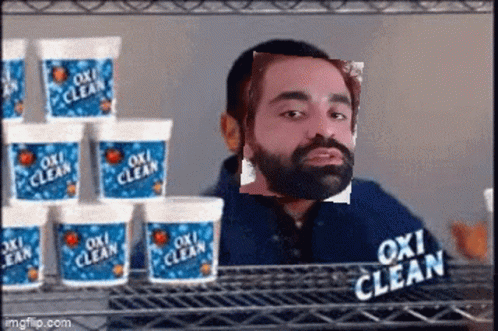 A Man With A Beard Is Standing In Front Of A Shelf Full Of Oxi Clean Containers GIF
