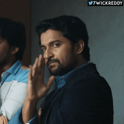 A Man With A Beard Is Standing In Front Of A Sign That Says ' 7Wickreddy ' On It GIF