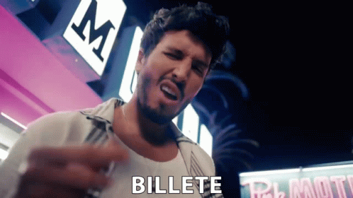 A Man With A Beard Is Standing In Front Of A Sign That Says " Billete " GIF
