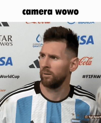 A Man With A Beard Is Standing In Front Of A Sign That Says Camera Owo GIF