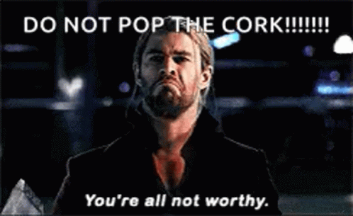 A Man With A Beard Is Standing In Front Of A Sign That Says `` Do Not Pop The Cork ! '' GIF