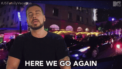 A Man With A Beard Is Standing In Front Of A Sign That Says Here We Go Again GIF