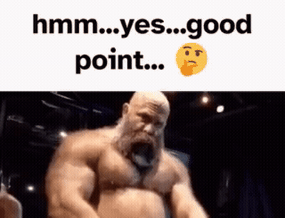 A Man With A Beard Is Standing In Front Of A Sign That Says Hmm Yes Good Point GIF