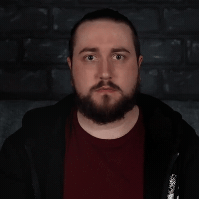 A Man With A Beard Is Standing In Front Of A Sign That Says " Lovely " GIF
