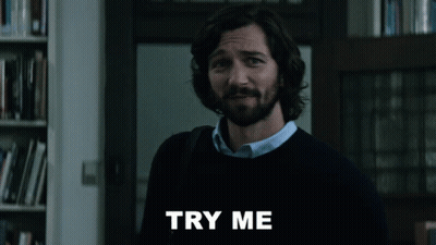A Man With A Beard Is Standing In Front Of A Sign That Says " Try Me " GIF