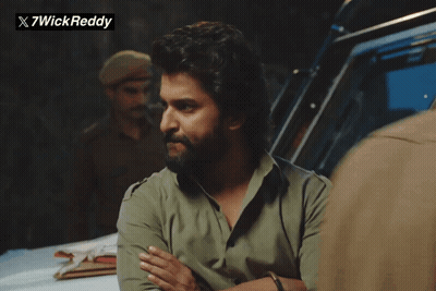 A Man With A Beard Is Standing In Front Of A Sign That Says X7wickreddy GIF
