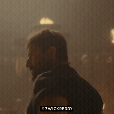 A Man With A Beard Is Standing In Front Of A Sign That Says X7wickreddy On It GIF