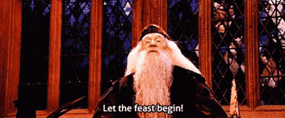 A Man With A Beard Is Standing In Front Of A Stained Glass Window And Says Let The Feast Begin . GIF
