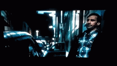 A Man With A Beard Is Standing In Front Of A Television Screen . GIF