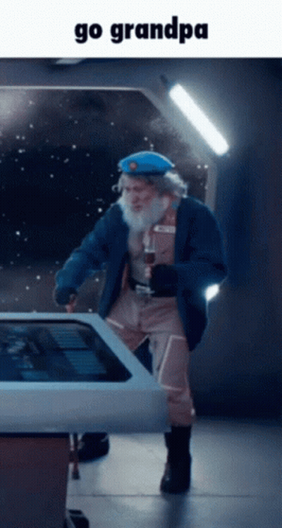 A Man With A Beard Is Standing In Front Of A Touchscreen With The Words Go Grandpa Below Him GIF