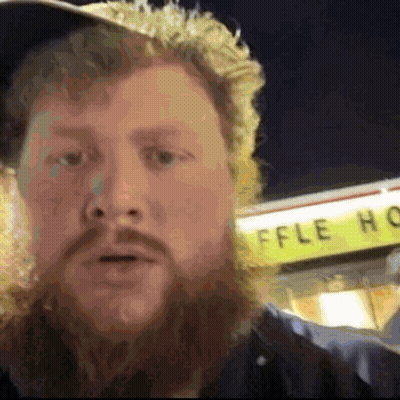A Man With A Beard Is Standing In Front Of A Waffle House GIF