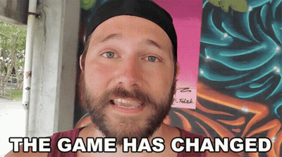 A Man With A Beard Is Standing In Front Of A Wall That Says The Game Has Changed On It GIF