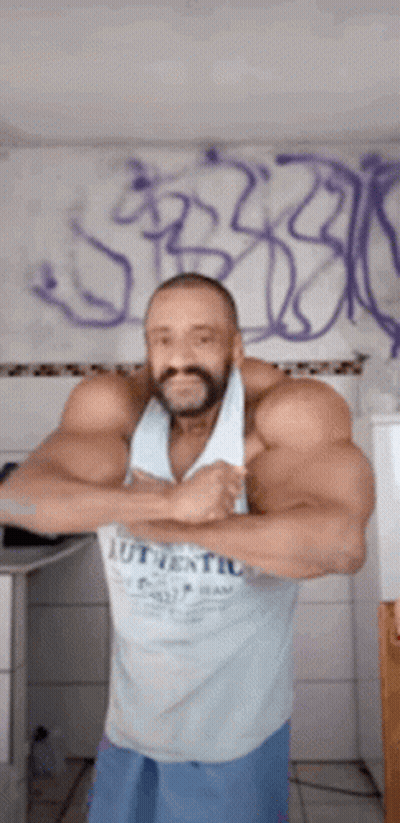 A Man With A Beard Is Standing In Front Of A Wall With Graffiti . GIF
