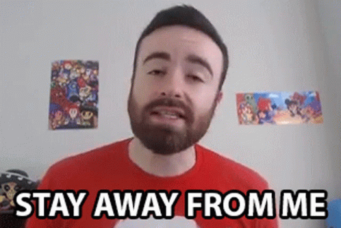A Man With A Beard Is Standing In Front Of A Wall With Posters On It And Says `` Stay Away From Me '' . GIF