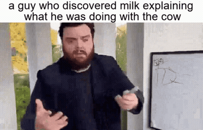 A Man With A Beard Is Standing In Front Of A Whiteboard Explaining What He Was Doing With The Cow . GIF