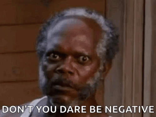 A Man With A Beard Is Standing In Front Of A Window With The Words `` Don 'T You Dare Be Negative '' . GIF