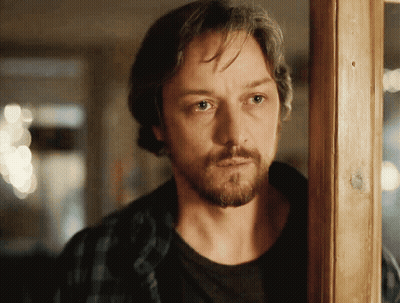 A Man With A Beard Is Standing In Front Of A Wooden Door GIF
