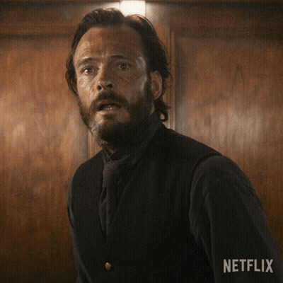 A Man With A Beard Is Standing In Front Of A Wooden Wall With Netflix Written On The Bottom Right GIF