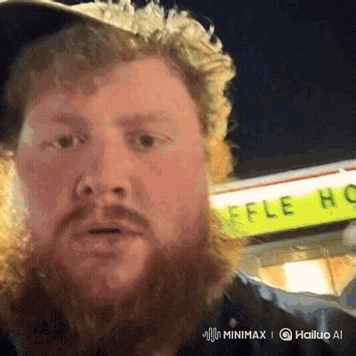 A Man With A Beard Is Standing In Front Of A Yellow Sign That Says Waffle House GIF