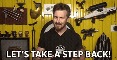 A Man With A Beard Is Standing In Front Of A Yellow Wall With Weapons And Toys . GIF